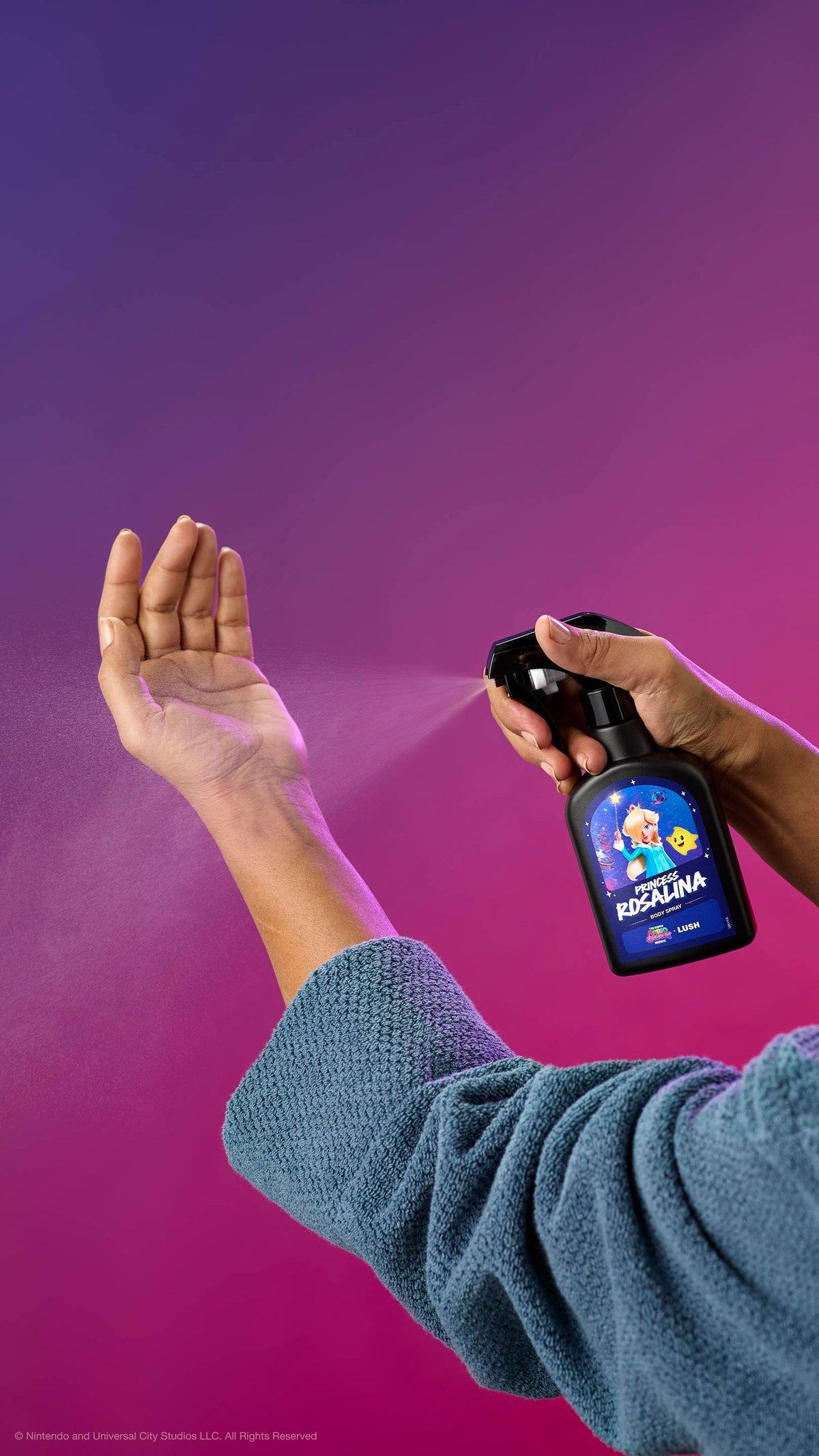 A person in a blue robe sprays Princess Rosalina body spray onto their inner wrist against a purple-pink gradient. The black bottle features a label with Princess Rosalina and a Luma.