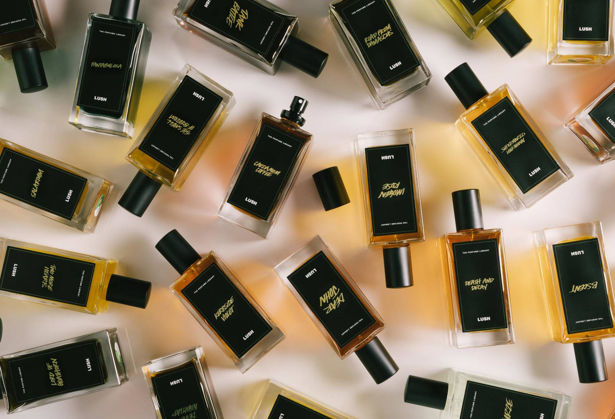 A number of black label perfume bottles are arranged randomly, with Cardamom Coffee in the centre, lid off, ready to spritz.