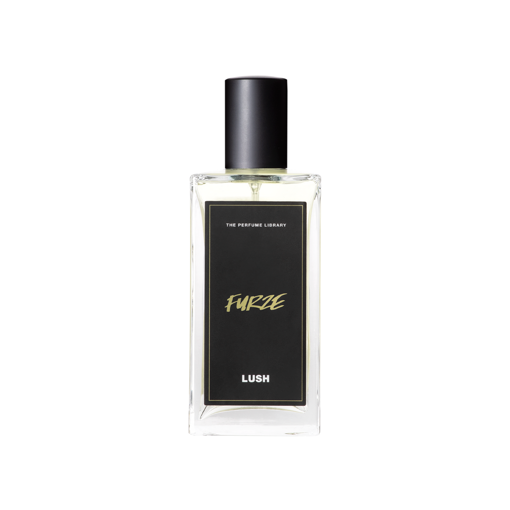 A glass perfume bottle filled with almost colourless liquid. A black label reads 'The Perfume Library' and 'Furze'.